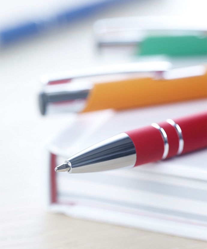 Metalkuglepenne i forskellige farver som ligger på en bog